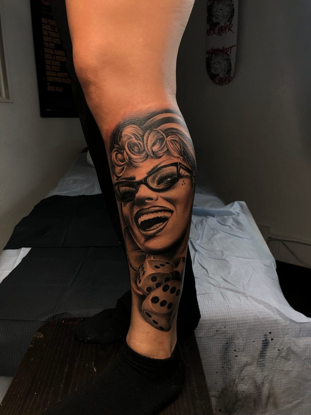 Black and grey laughing face with dice trailing down a calf.
