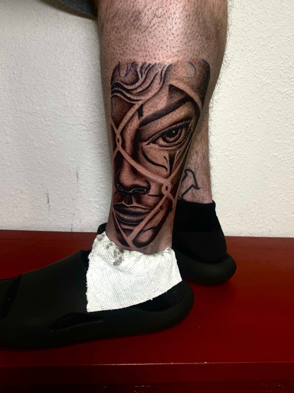 Black and grey portrait rendered in fractured glass panels down a leg.